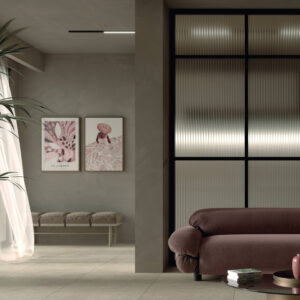Camera da letto moderna con pavimento Block Beige effetto cemento beige, arredi scuri, divano bordeaux e pareti grigio scuro con quadri decorativi
