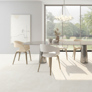 Sala da pranzo luminosa con pavimento Isea White effetto marmo bianco, tavolo rotondo bianco con sedie beige, lampadario moderno e grande finestra con vista su giardino