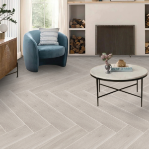 Soggiorno moderno con pavimento Natural Grey effetto pietra grigio naturale in formato 100x100, poltrona blu, tavolino rotondo e camino contemporaneo