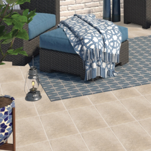 Terrazza esterna moderna con pavimento Brenta Beige effetto pietra beige chiaro, divano da esterno in rattan grigio scuro con cuscini blu, tappeto geometrico blu e grigio, lanterna decorativa e piante verdi in ambiente outdoor contemporaneo